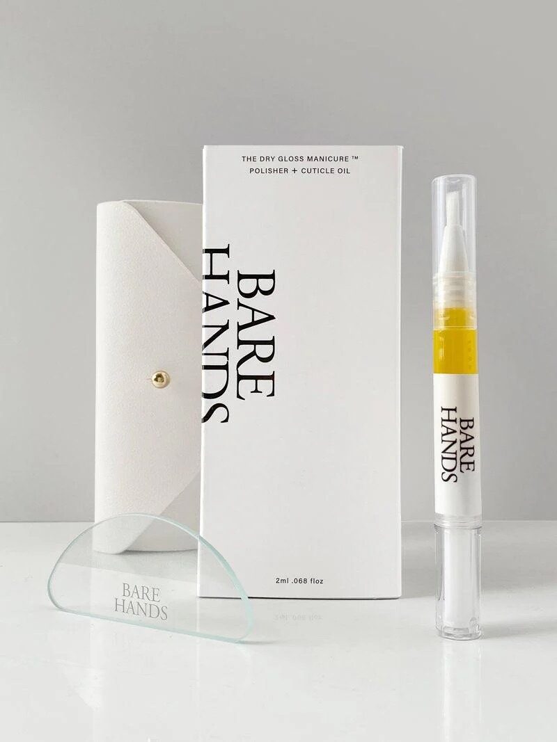 A manicure kit including a white case, a glass nail tool, a polisher and cuticle oil pen, and a white product box labeled "Bare Hands" on a plain surface.