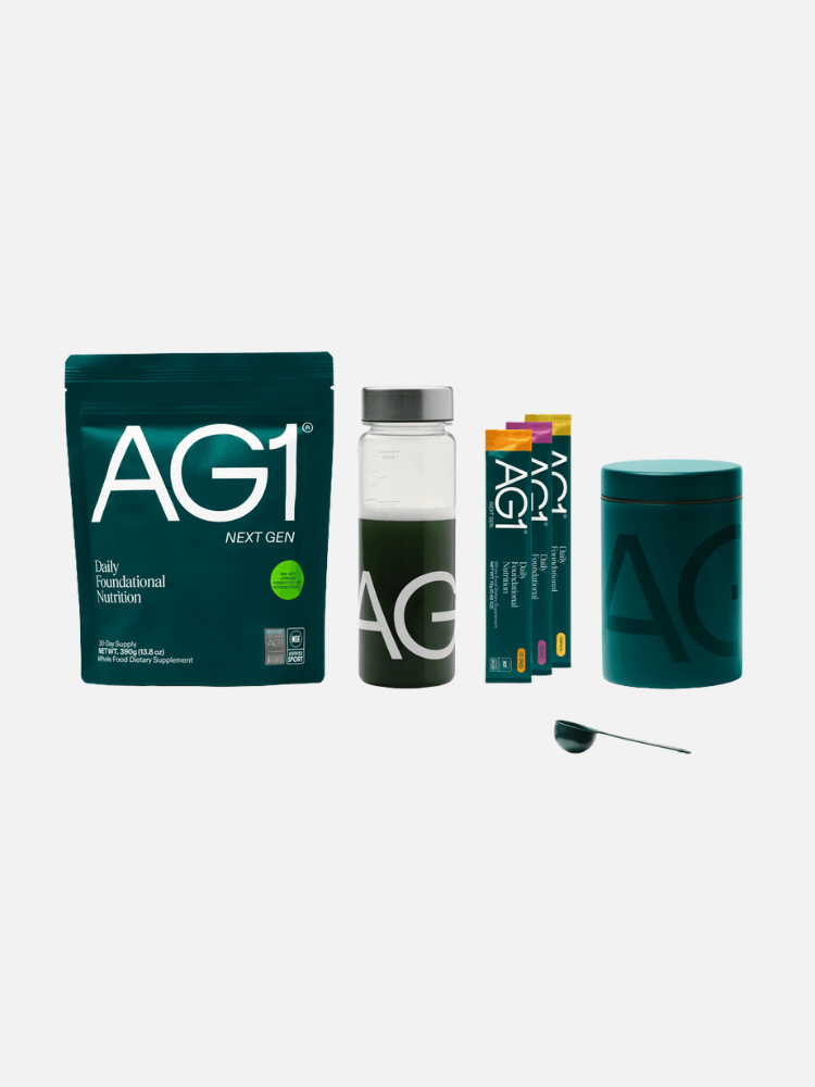 AG1 nutrition powder bag, a bottle with green drink, three single-serve packets, a large canister, and a scoop, all on a white background.