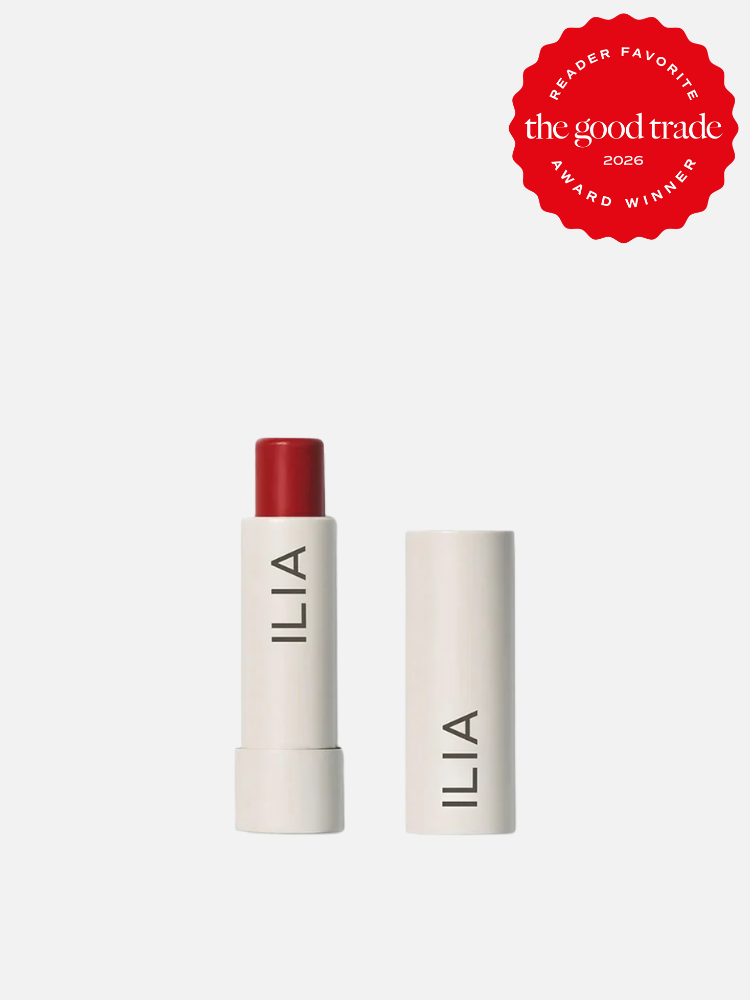 A red ILIA lipstick with the cap removed, placed next to the closed cap, on a white background. A red "The Good Trade 2026 Award Winner" badge appears in the top right corner.