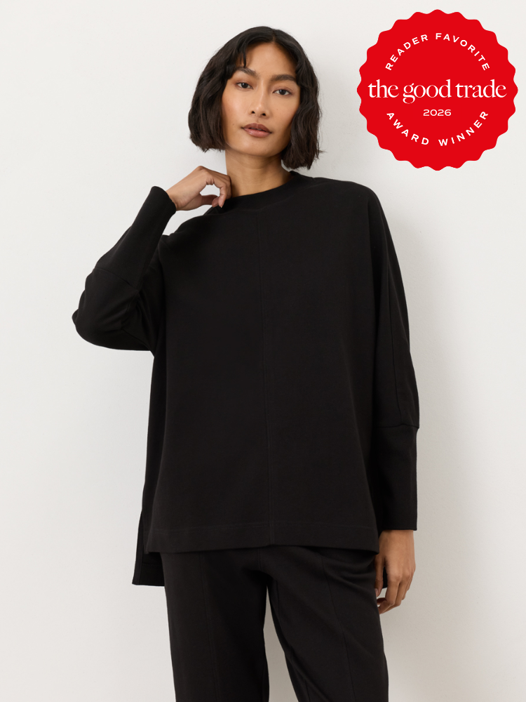 A person wearing a loose-fitting black long-sleeve top and black pants stands against a white background. A red badge in the corner reads "the good trade award winner 2026.