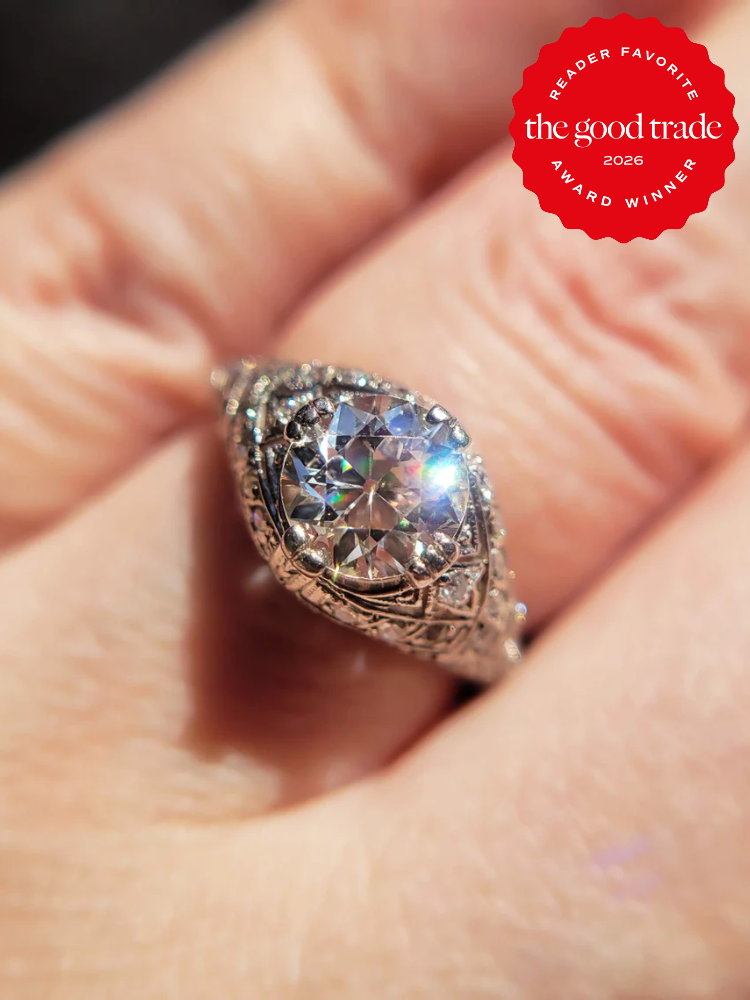 A close-up of an ornate diamond ring on a hand, with a red badge in the corner that reads "The Good Trade Reader Favorite Award Winner 2026.